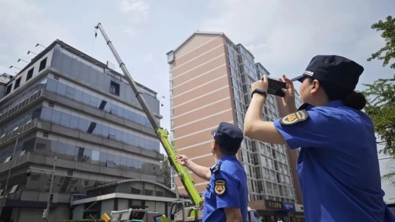 在北京市东城区某酒店楼顶违法建设拆除现场，城管队员进行执法取证。