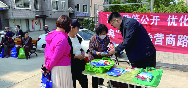 朝阳图，龙城区司法局工作人员正在向辖区居民发放各类民法典宣传资料